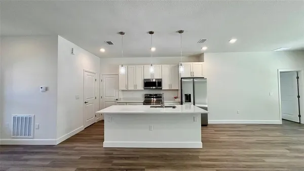 a view of kitchen with kitchen island white cabinets and stainless steel appliances