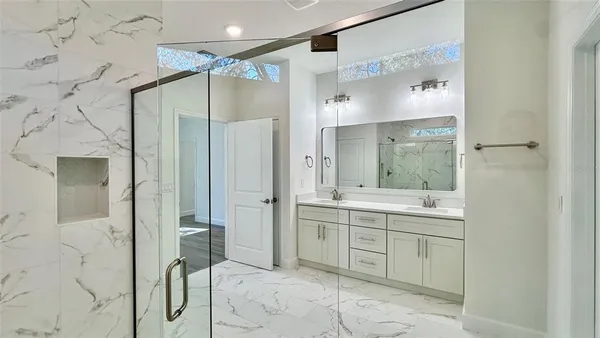 a bathroom with a mirror sink and glass door shower