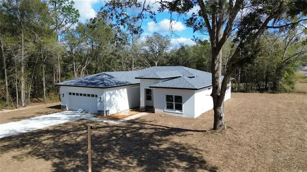 a view of a white house with a large tree