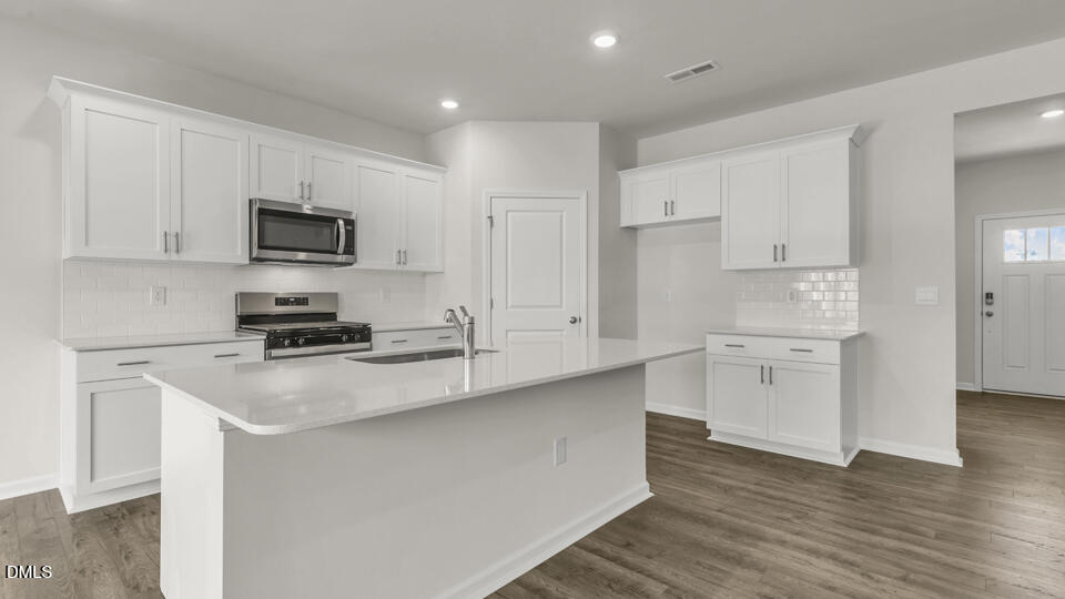 1281 Pavo Path Wendell, NC 27591 - Photo 10 of 54 a kitchen with stainless steel appliances a stove a sink a refrigerator a microwave and cabinets