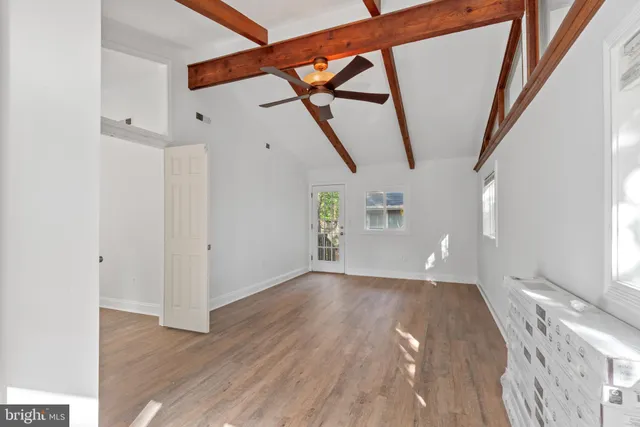 a view of an empty room with wooden floor and door