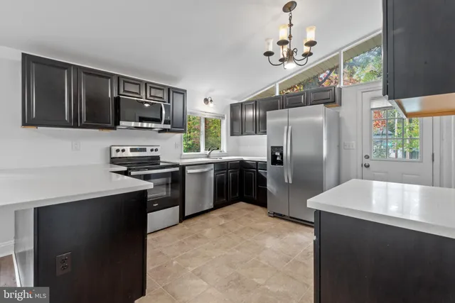 a kitchen with stainless steel appliances a refrigerator a stove a sink a microwave a dining table and chairs