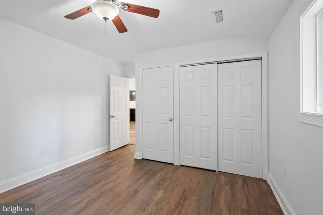 an empty room with wooden floor cabinet and windows
