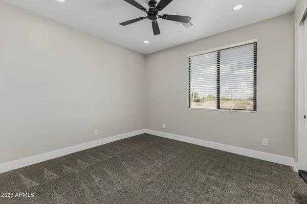 an empty room with a ceiling fan and carpet