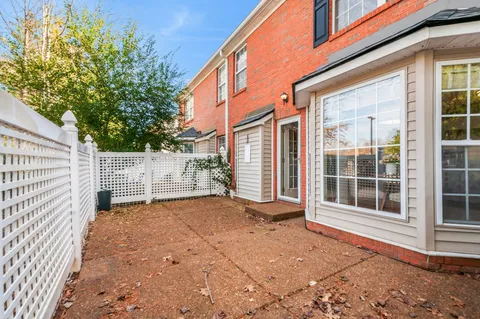 a view of backyard with large trees and wooden fence