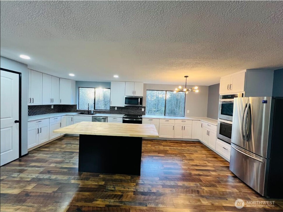 1412 Centralia Alpha Road Chehalis, WA 98532 - Photo 5 of 37 a large kitchen with kitchen island a sink dishwasher a refrigerator and a stove with wooden floor
