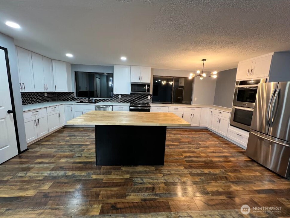 1412 Centralia Alpha Road Chehalis, WA 98532 - Photo 6 of 37 a large kitchen with kitchen island granite countertop a stove top oven a sink a counter space and cabinets