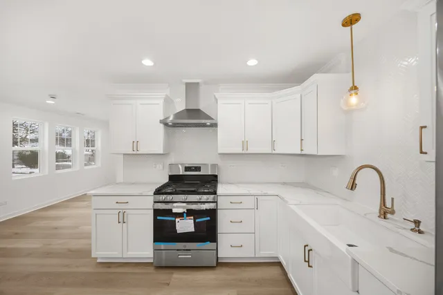 a kitchen with stainless steel appliances a stove and white cabinets