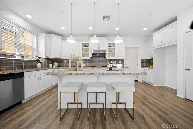 a kitchen with stainless steel appliances granite countertop a white cabinets and wooden floor