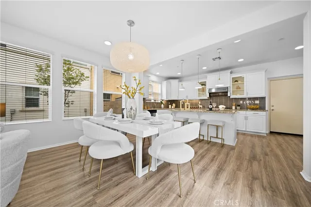 a dining room with stainless steel appliances kitchen island granite countertop a table chairs and a refrigerator