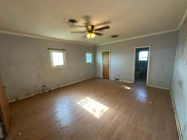 an empty room with wooden floor and windows