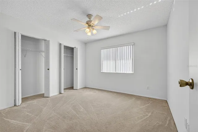 an empty room with windows and fan