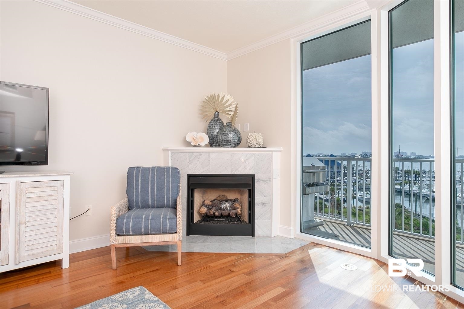 27800 Canal Road, Unit 411 Orange Beach, AL 36561 - Photo 26 of 49 Hardwood flooring throughout featuring a corner-set fireplace with a marble surround and hearth, complemented by crown molding