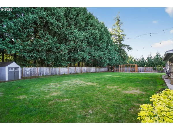 a view of a backyard with grass and a white fence