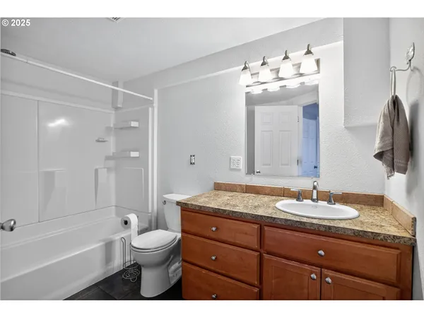 a bathroom with a granite countertop sink mirror toilet and bathtub