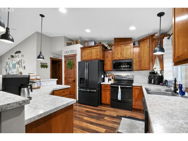 a kitchen with stainless steel appliances kitchen island granite countertop a refrigerator a stove top oven and a sink