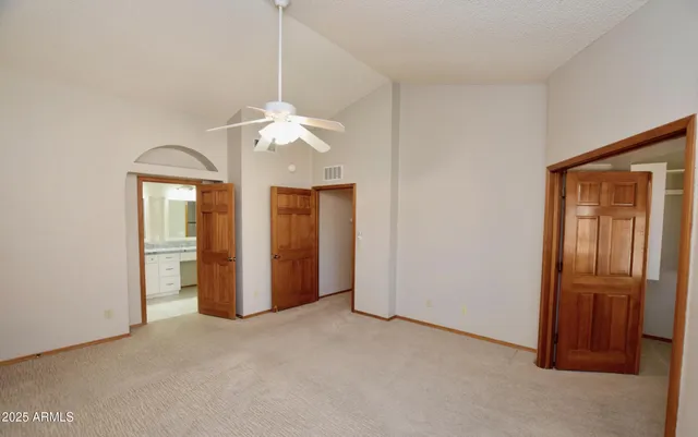 an empty room with chandelier fan and windows