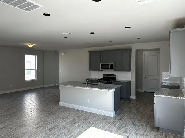 a kitchen with granite countertop a sink a counter top space stainless steel appliances and cabinets