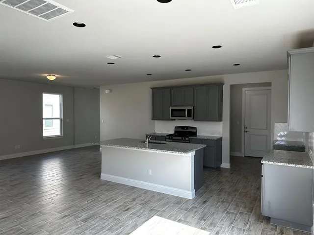 a kitchen with granite countertop a sink a counter top space stainless steel appliances and cabinets