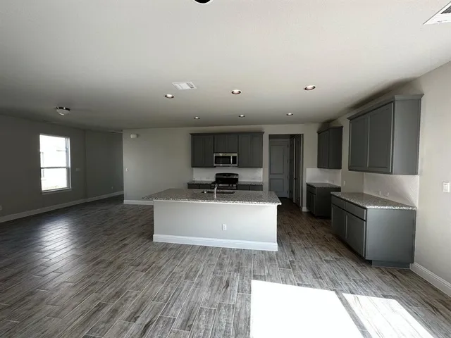 a large kitchen with stainless steel appliances granite countertop a stove a refrigerator a sink a microwave and wooden cabinets