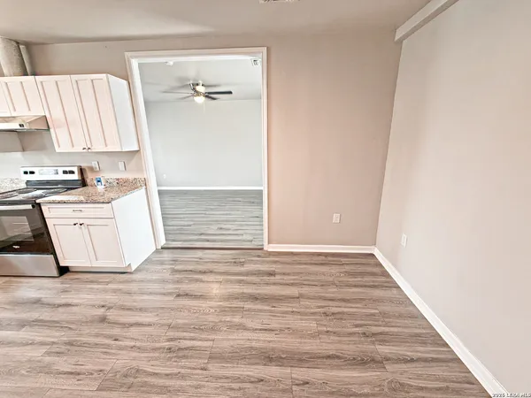 a view of a kitchen with wooden floor and a hallway