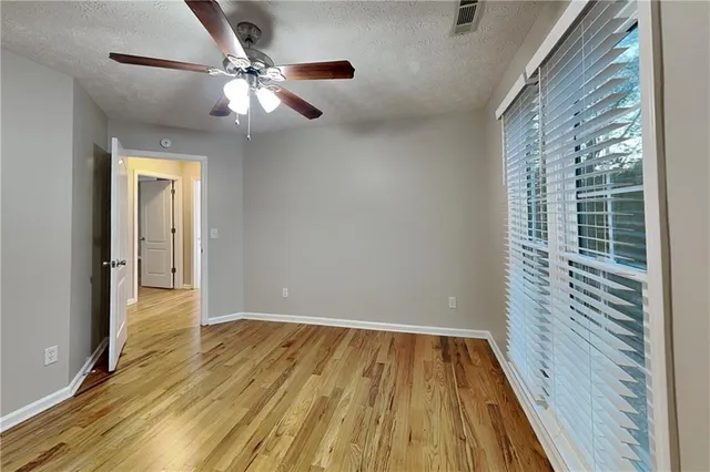 a view of an empty room with wooden floor and a window