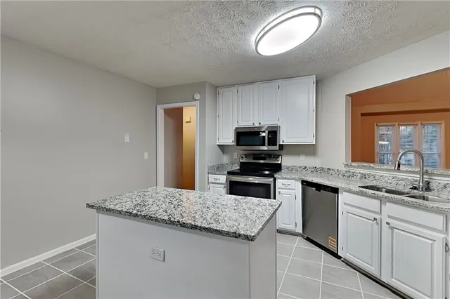a kitchen with kitchen island granite countertop stainless steel appliances a sink stove refrigerator and cabinets