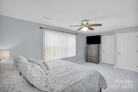 a spacious bedroom with a bed and a tv