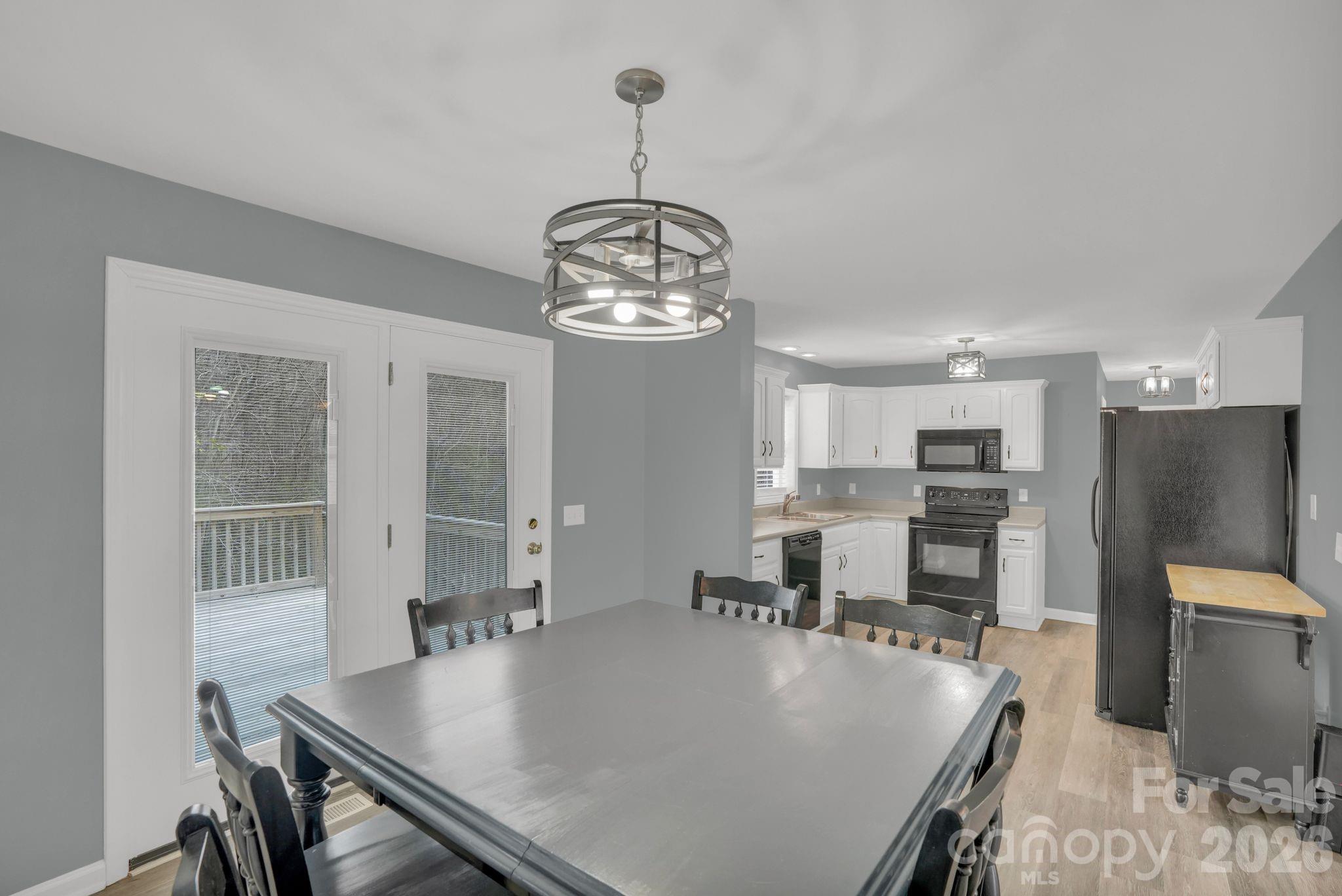 10425 Idlewild Road Matthews, NC 28105 - Photo 7 of 25 a dining room with wooden floor a chandelier a wooden table and chairs