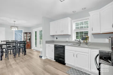 a kitchen with stainless steel appliances granite countertop a stove a sink a dining table and chairs with wooden floor