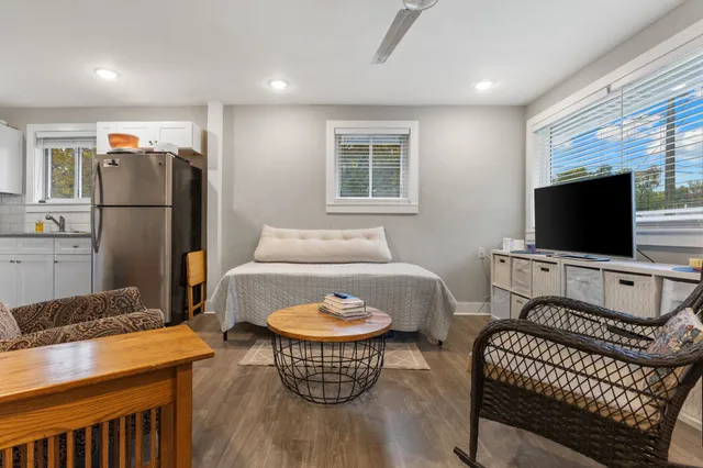 a living room with furniture a flat screen tv and a refrigerator