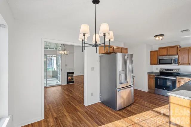 a kitchen with stainless steel appliances granite countertop a refrigerator a stove and a wooden floors
