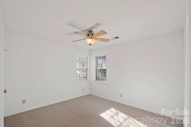 an empty room with windows and chandelier fan