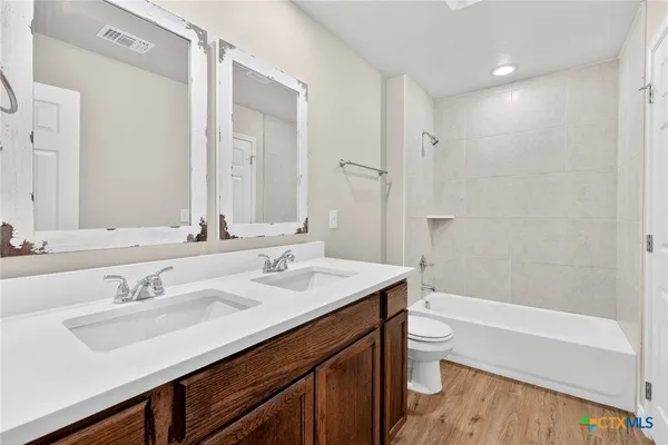 a bathroom with a sink a toilet a large mirror and shower