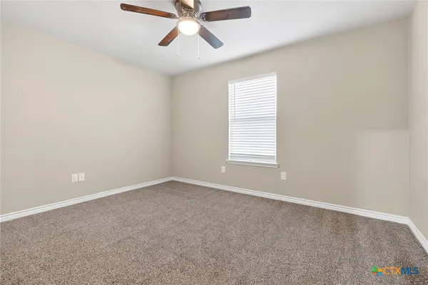 an empty room with a window and a fan