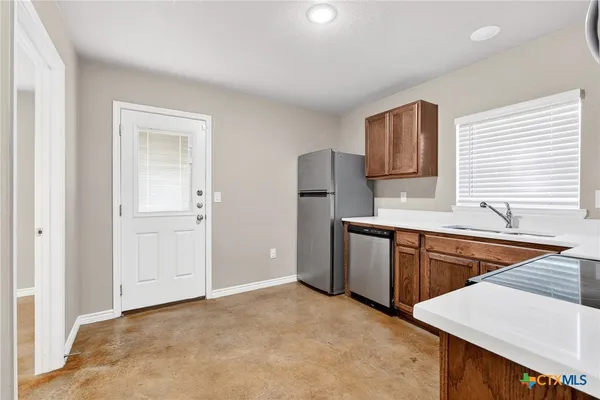 a kitchen with stainless steel appliances granite countertop a refrigerator sink and wooden cabinets