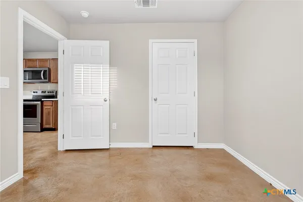 an empty room with kitchen and stainless steel appliances