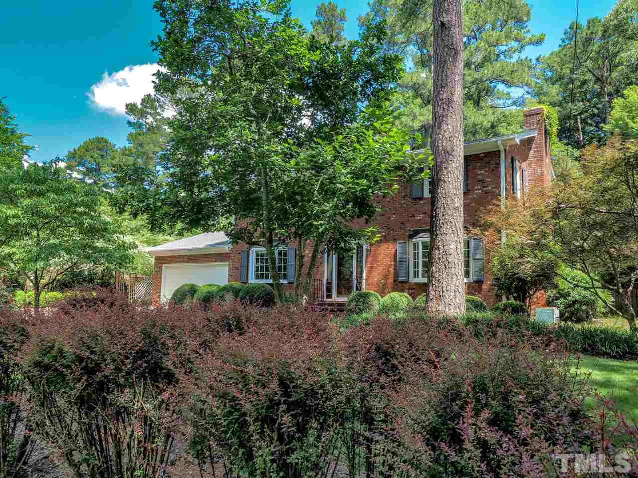 a view of a house with a yard and large trees