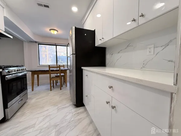 a kitchen with granite countertop a stove a sink and a refrigerator
