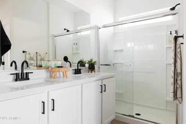 a bathroom with a double vanity sink mirror and shower