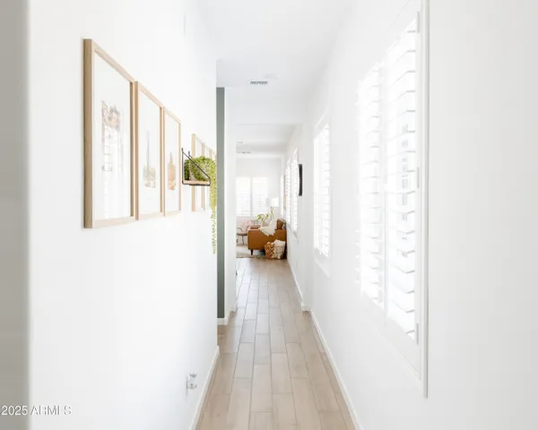 a view of a hallway with wooden floor and a bathroom