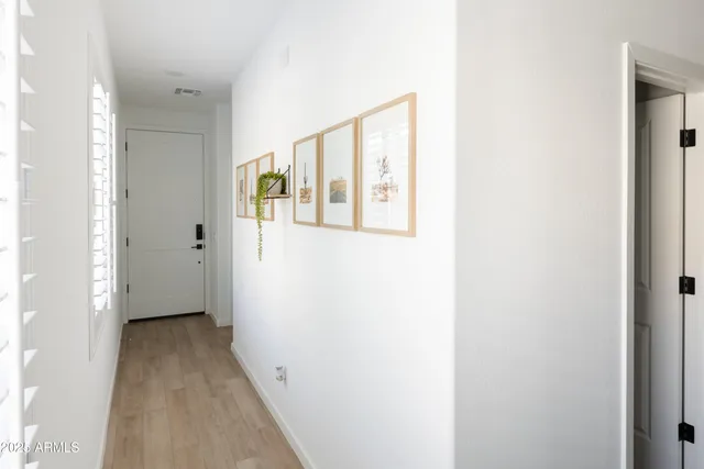 a view of a hallway with wooden floor and a bathroom