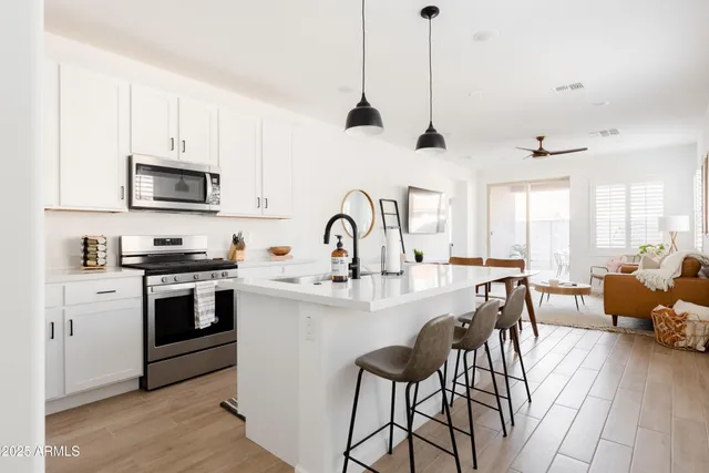 a kitchen with stainless steel appliances granite countertop a stove a sink dishwasher a dining table and chairs with wooden floor