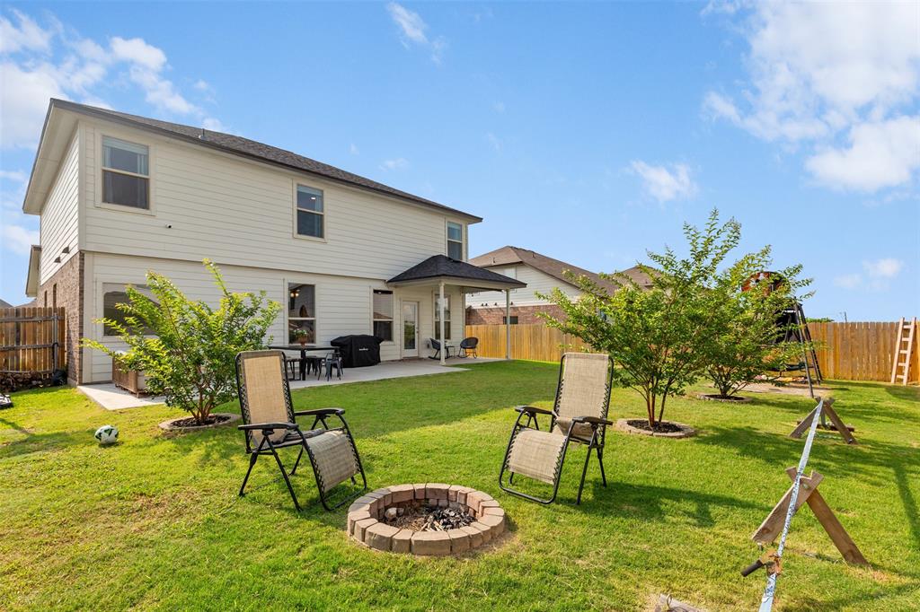 3105 Marston Road Lorena, TX 76655 - Photo 33 of 40 Expansive backyard featuring a manicured lawn, established trees, and a brick-ringed fire pit