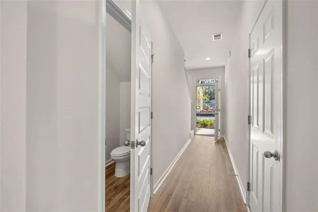a view of a hallway with wooden floor and a bathroom