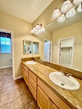 a bathroom with a granite countertop double vanity sink and a mirror