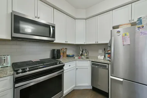 a kitchen with stainless steel appliances white cabinets and a stove a refrigerator a sink