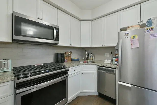 a kitchen with stainless steel appliances white cabinets and a stove a refrigerator a sink
