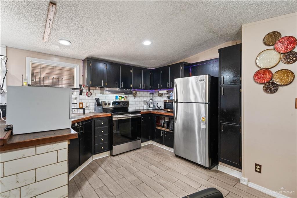 48 Gladiola Street Alamo, TX 78516 - Photo 9 of 14 a kitchen with stainless steel appliances granite countertop a refrigerator stove a sink dishwasher and a refrigerator with wooden cabinets