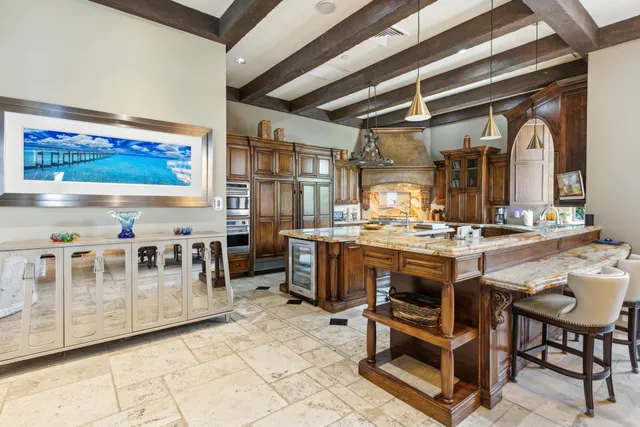 a kitchen with stainless steel appliances granite countertop a sink a stove a refrigerator cabinets and chairs